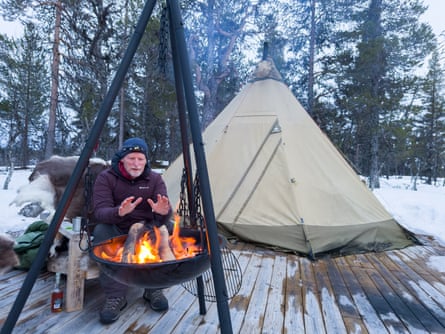 The writer warms his hands on a fire outside a Sami herder’s tipi.