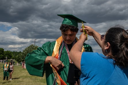 a woman fixing a young man graduation cap