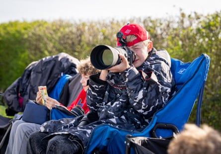 Boy looks through telescopic camera lens.