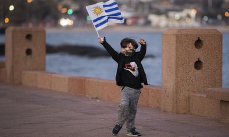 A boy wearing a protective face mask waves a Uruguayan national flag in Montevideo, Uruguay.