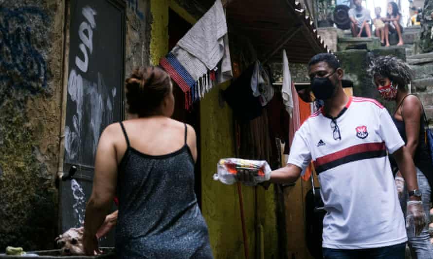 Community leader William da Rocinha, wearing a protective face mask and gloves, delivers aid donations to a resident of the Rocinha favela in Rio de Janeiro this week.