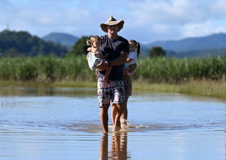 John Lawrence with children Harlow and Aria inspect a flooded road near their home in Dungay