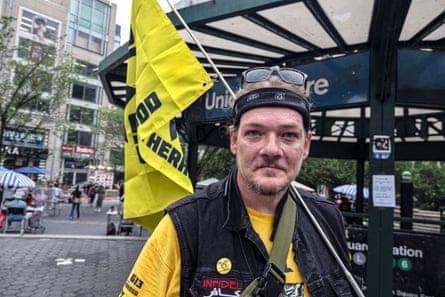 a man successful a t-shirt and vest holds a yellowish flag