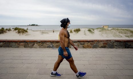 A man wearing a mask as a precaution against the spread of the new coronavirus, walks by the seaside in Montevideo, Uruguay, on Tuesday.