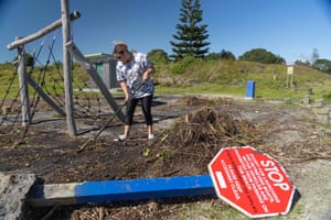 A woman clears debris from a storm surge at a playground at Waihi Beach