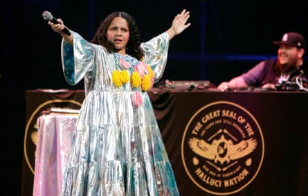 Pimiento spreads her arms wide on stage, in a silvery tiered dress with wide sleeves