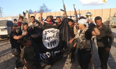 Iraqi security forces and allied Shiite militiamen celebrate as they hold a flag of the Islamic State group they captured in Tikrit, 80 miles (130 kilometers) north of Baghdad, Iraq, Tuesday, March 31, 2015.
