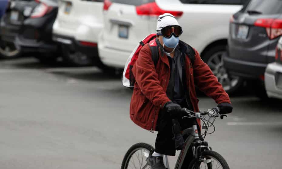 A person wearing a mask bikes away from the Life Care Center of Kirkland in Washington on 3 March. 