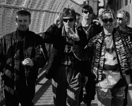 A black and white shot of the band walking along a metal walkway with a mesh railing