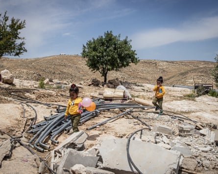 Two Palestinian girls play on the rubble of a demolished building in the village of Khalet Al-Daba’a