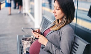 Pregnant woman on the phone while waiting for a train. Photograph by: Xsandra/Getty