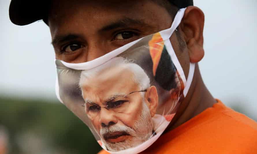 An Indian man wears a mask with a picture of Modi