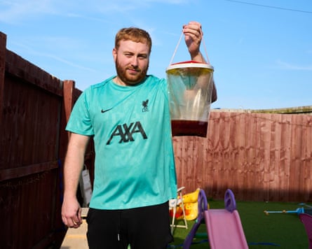 A man holds up a fly-catching bag in a back garden