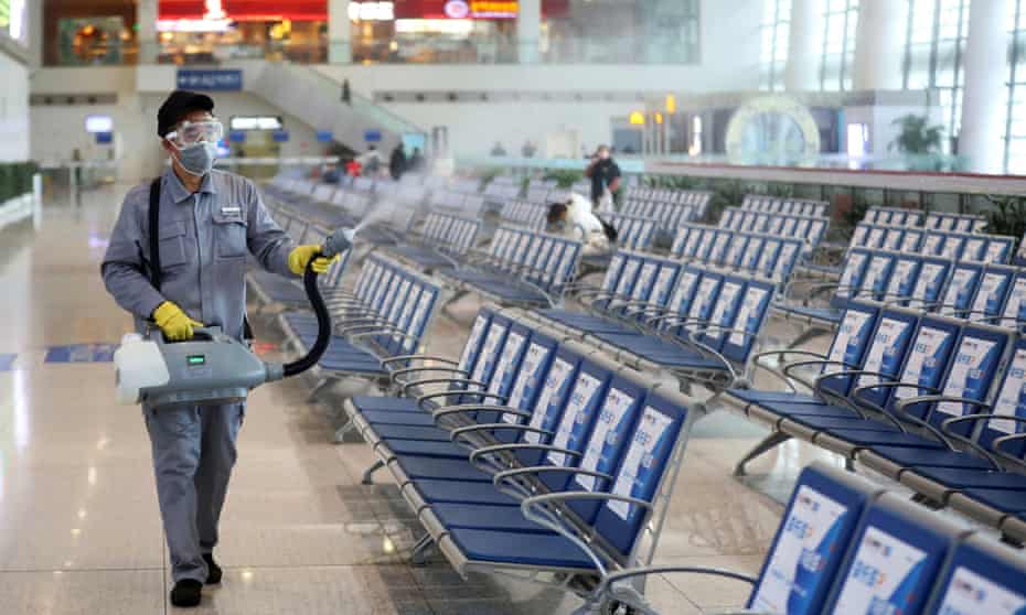 A worker in protective mask disinfects a waiting hall at the Nanjing Railway Station, in Nanjing