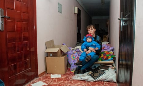 A woman with a baby sits in a general corridor of a building that is used as a bomb shelter, as she isn’t able to reach the basement in time during shelling, in Kharkiv, Ukraine, 10 April 2022.
