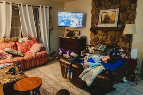 A man reclines on a couch watching a baseball game on TV