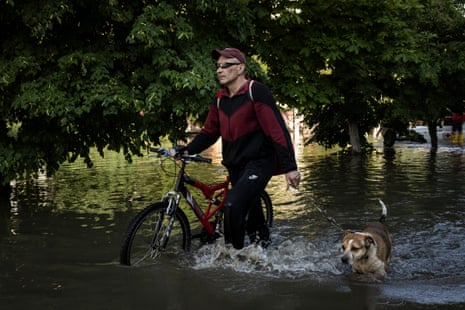 A man with his bike and dog attempt to travel through flooded Kherson.