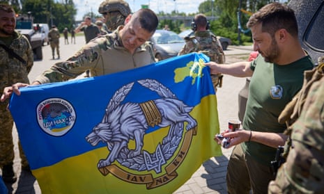 A Ukrainian serviceman shows Volodymyr Zelenskiy a national special ops flag in Donetsk.