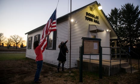 Election judges Yvonne Latuff (L) and Eliza Mark hang an American flag outside a polling place before it opens on November 3, 2020 in Hampton, Minnesota.