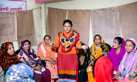 A woman stands in front of a group of at least eight other women to make a speech.