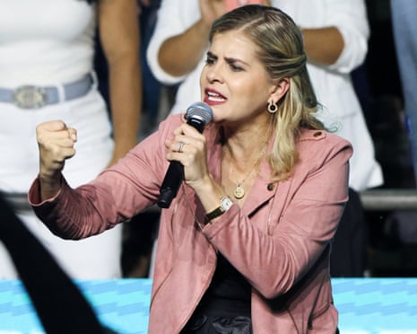 Laura Fernández in pink jacket with mic and raised fist