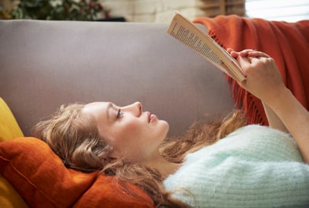 Young woman lying on sofa reading
