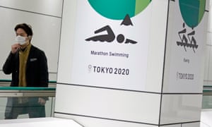 A passerby wearing a protective mask walks past a postponed Tokyo Olympic Games advertising boards in Tokyo, Japan, 12 November 2020.