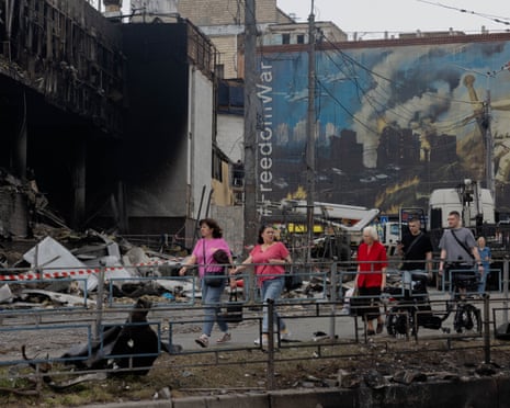 Local residents walk by a damaged shopping center following Russian strikes in Kyiv.