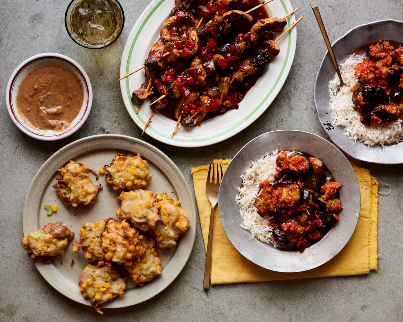 Vegan Indonesian snacks: aubergine in spicy sambal (right), sweetcorn fritters (left), and marinated mushroom skewers (top).