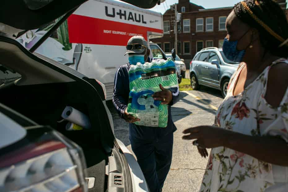 Volunteers load cases of water into residents' cars at the clean water giveaway at Pinkney's church.