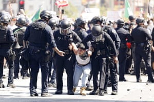 A demonstrator is detained by a group of officers