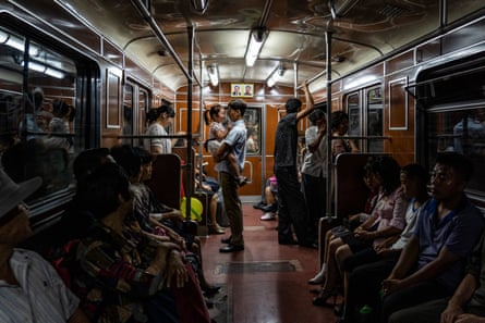 People ride the metro in Pyongyang under the watch of portraits of Kim Il-sung and Kim Jong-il