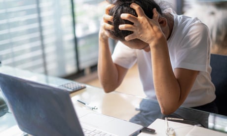 Tired young woman holding her head as she sits in front of a laptop
