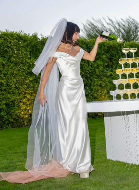 she is pouring champagne into glasses arranged in a pyramid.