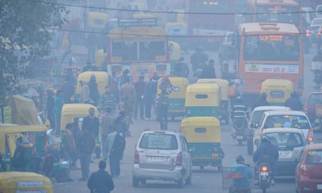 Indian commuters travel on a polluted road near a bus terminus in Delhi. 