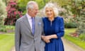 King Charles  and Queen Camilla talk to each other, arm in arm, in a garden