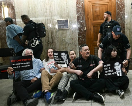 Demonstrators protesting the lack of funding for PEPFAR (President’s Emergency Plan for AIDS Relief) are detained by police officers in the hallway outside of Marco Rubio’s hearing room.