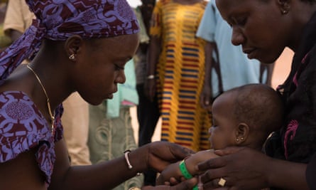 A community health worker in Mali measures a child’s arm to check for malnutrition