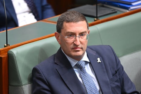 A man with short hair, glasses and a blue suit.