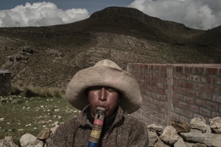 A rural Peruvian man in a hat playing a traditional pipe