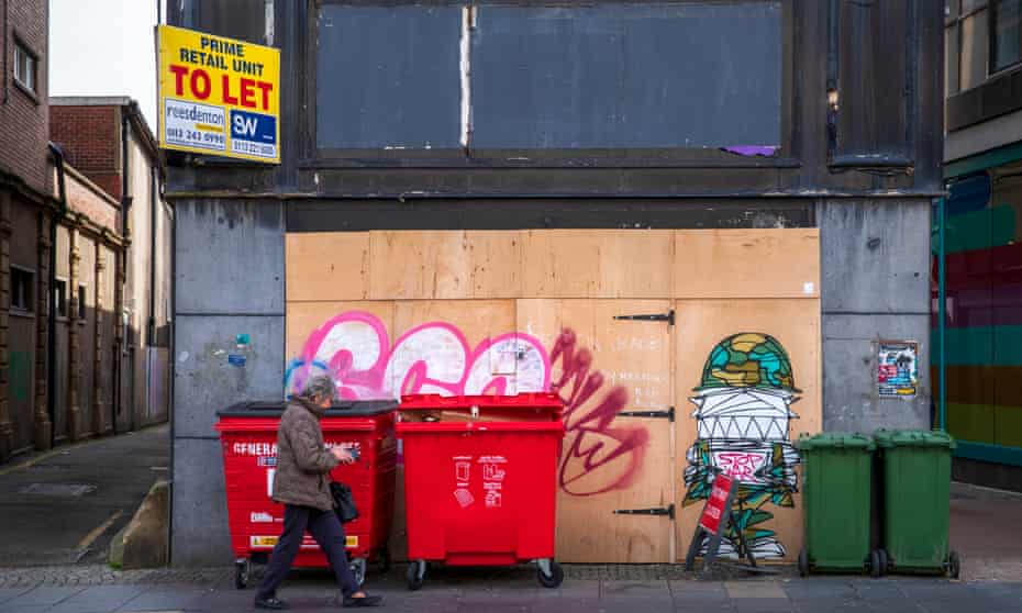 A woman walks past an empty retail unit and graffiti in Sheffield city centre.