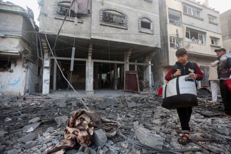 A boy carrying a bag picks his way through the rubble in the street in Khan Younis