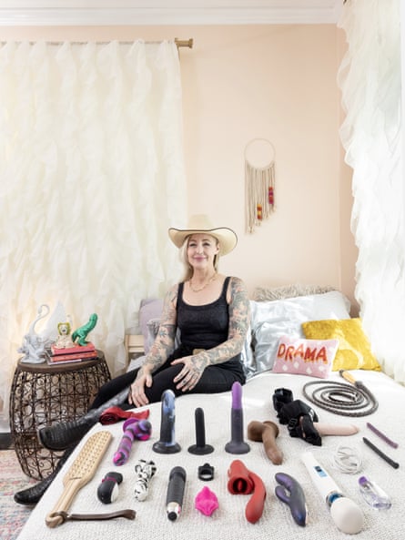 Photograph of Griffon wearing a cowboy had and sat on a bed with all her sex toys laid out on it