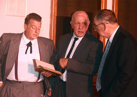 three men in suits look at a book