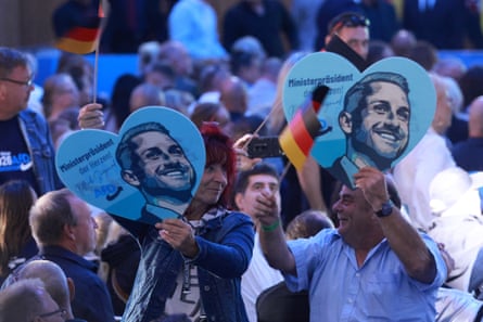 People wave Germany flags and hold heart-shaped placards depicting Ulrich Siegmund