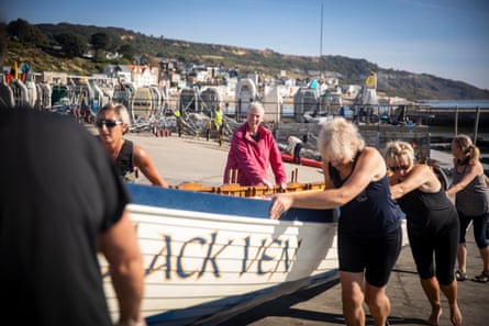Femmes portant un bateau sur le sable loin de l'eau