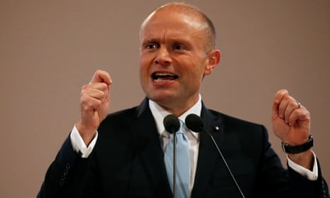 Joseph Muscat raises both hands while talking into a microphone
