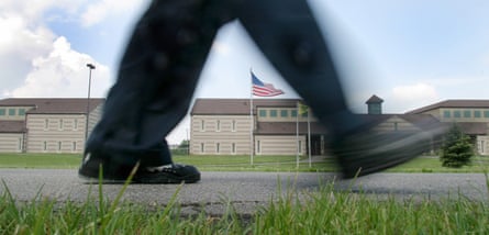 Closeup shot of a pair of feet in the action of walking. In the background, the buildings of a correctional facility can be seen.