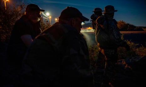 Men including Jim Benvie, a spokesman for the militia calling itself the United Constitutional Patriots, share cigarettes while patrolling the US-Mexico border in Sunland Park, New Mexico last month.