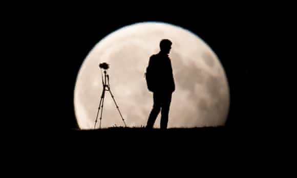 A man stands in front of the moon.